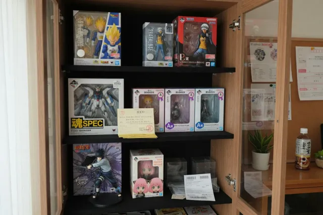 Bandai collectibles displayed in a Japanese collector shop, including figures, model kits, and capsule toys