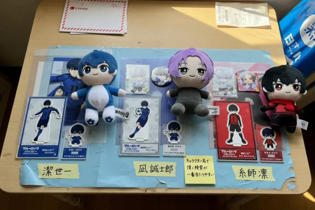 Blue Lock character acrylic stands and plush toys arranged by player on a Japanese marketplace