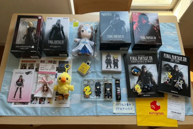 A Japanese Final Fantasy merchandise display with character figures, plush toys, art books, and keychains arranged by series