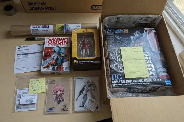 Several Gundam purchases from Japan packed together for international shipping, including kits, figures, manga, and acrylic stands