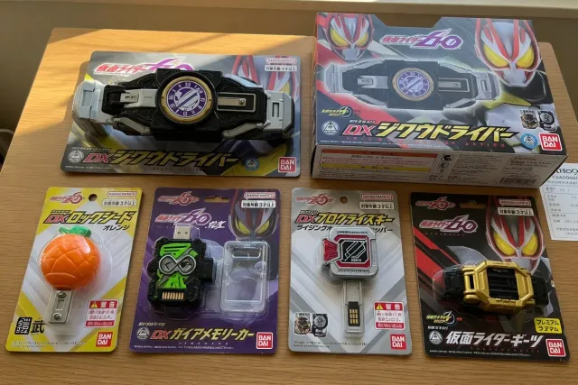 Kamen Rider transformation belt and collectible transformation items arranged beside their packaging