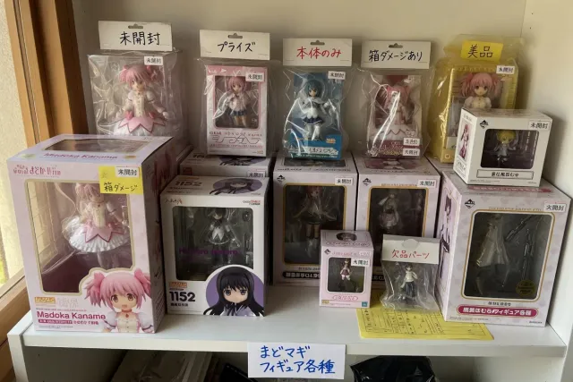 Boxed Madoka Magica figure collection with scale figures, Nendoroids, and prize figures on a Japanese seller shelf