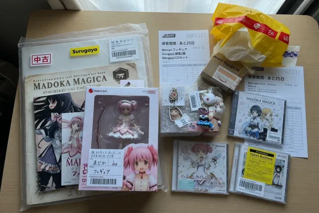 Several packed Madoka Magica merchandise purchases including manga, music CDs, keychains, and figures ready for consolidation