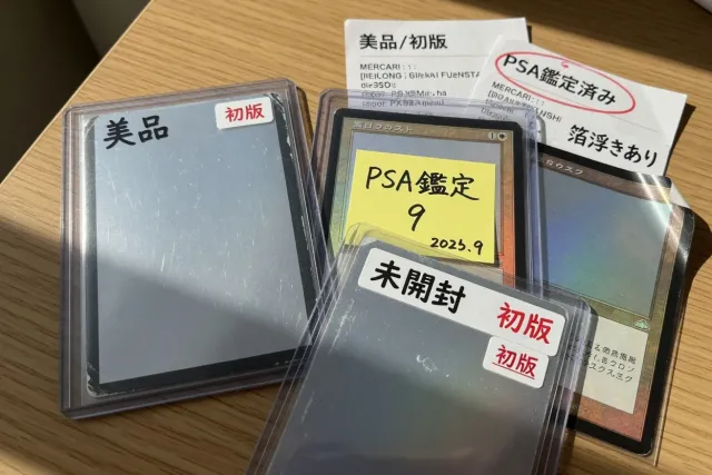 Close-up of Magic: The Gathering single cards in sleeves showing Japanese condition labels