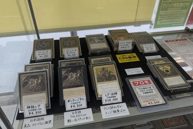 Japanese Magic: The Gathering cards displayed in a card shop showcase with price tags