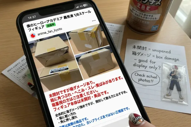A phone showing a Japanese My Hero Academia figure listing with condition notes and product photographs