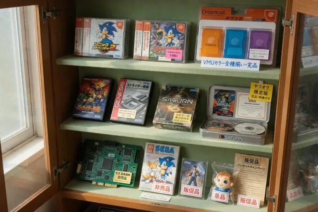 Rare SEGA promotional goods, Japanese arcade items and boxed Dreamcast games displayed in a collector cabinet